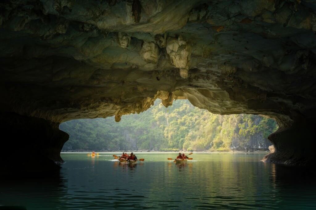 tourist exploring calm tropical bay with limestone mountains by kayak